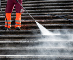 Man Pressure washing steps of commercial building